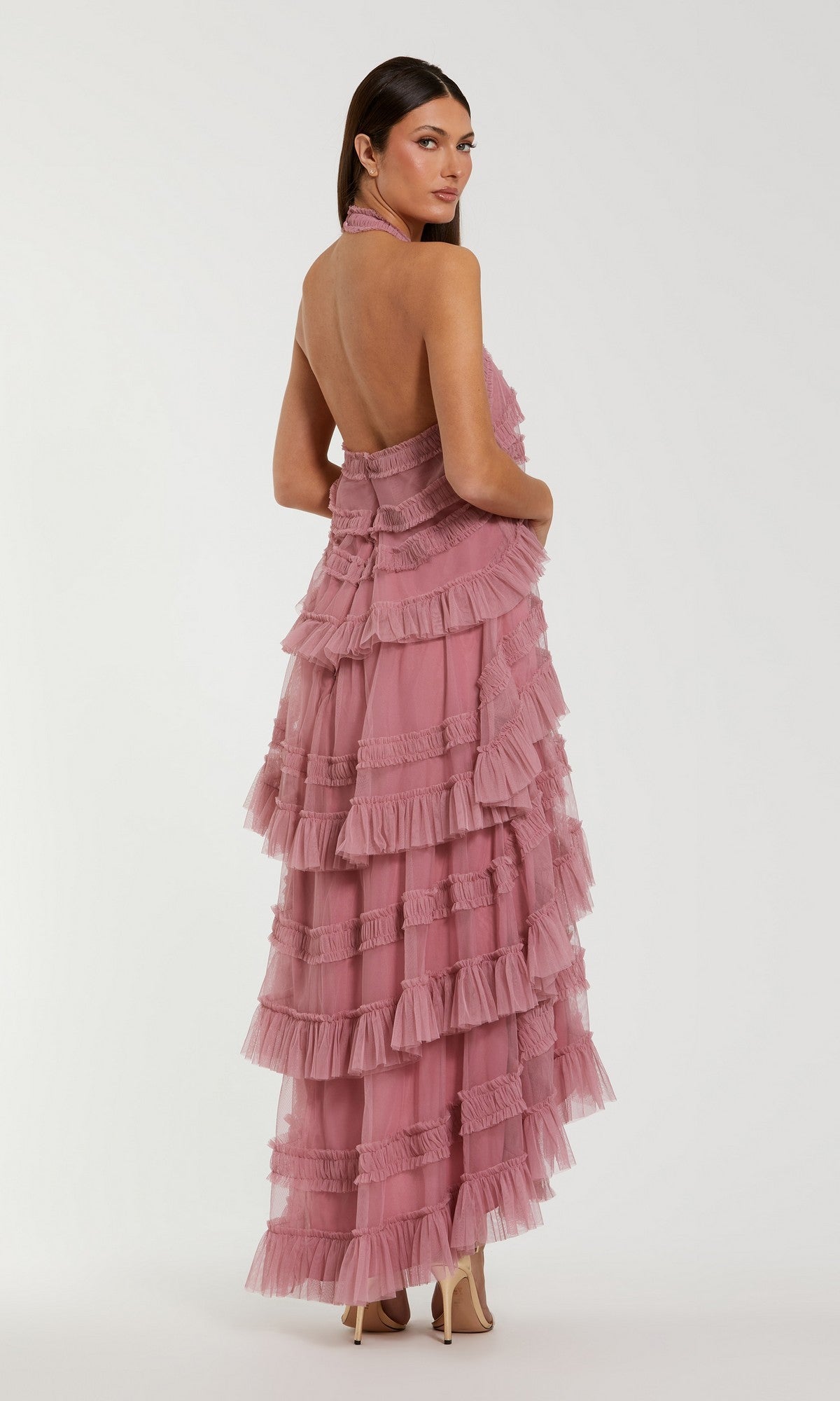 Woman in the Tea-Length Party Dress: Mac Duggal 8276, a sleeveless, backless mauve dress featuring a tiered ruffle design and high-low hemline, stands facing away while looking over her shoulder.